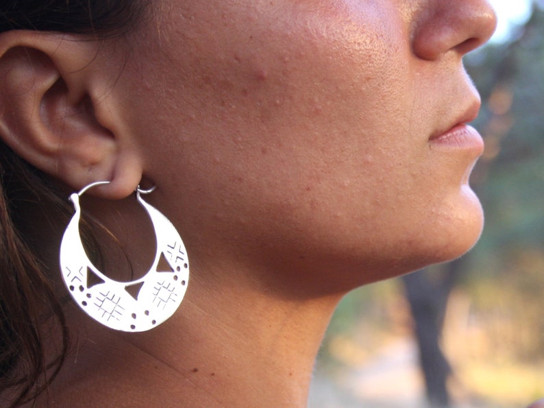 Woman wears Indian silver earrings. Indian silver jewelry. Indian hoop earrings.