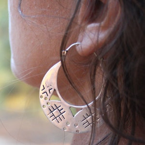 A closer shot of the woman wearing the tribal silver hoop earrings. You can see all the details of the openwork. Earrings with original geometric design, with triangles, stripes, circles...