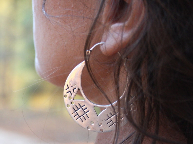 A closer shot of the woman wearing the tribal silver hoop earrings. You can see all the details of the openwork. Earrings with original geometric design, with triangles, stripes, circles...