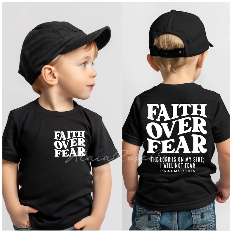 Puede incluir: Dos ni&ntilde;os con camisetas negras con la frase "Faith Over Fear" impresa en blanco. Una camiseta tiene la frase en la parte delantera y la otra tiene la frase en la parte posterior con el texto adicional "The Lord is on my side; I will not fear. Psalms 118:6".