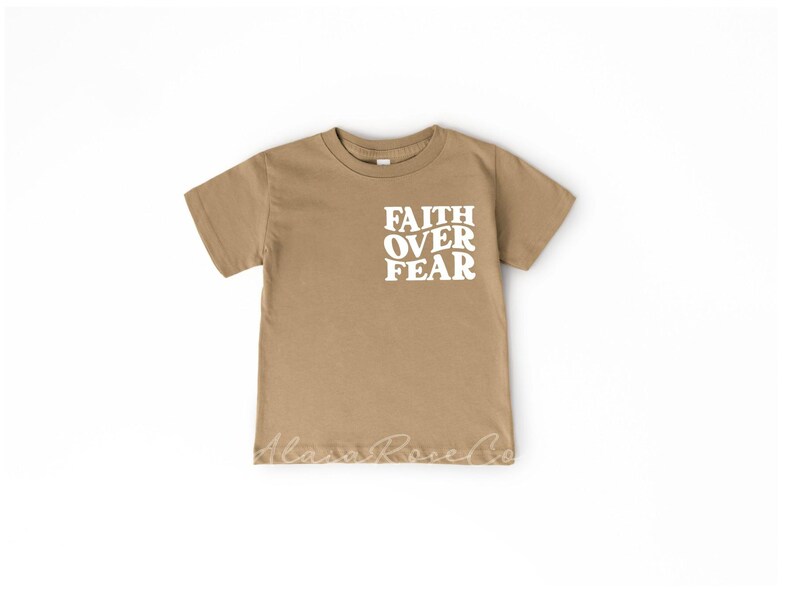 Puede incluir: Una camiseta de manga corta de color marr&oacute;n claro con las palabras "FAITH OVER FEAR" impresas en blanco en la parte delantera.