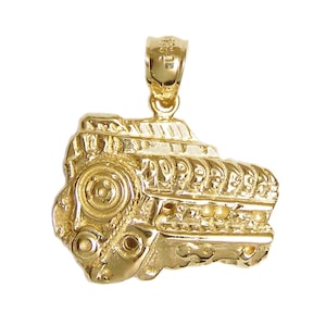 May include: A gold-colored pendant shaped like a detailed engine block. The pendant is a detailed replica of a car engine.