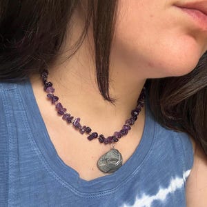 Collar artesanal de cuentas de vidrio dorado y amatista con colgante de concha marina auténtica envuelto en alambre.