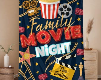 May include: A navy blue blanket with a movie night theme. The blanket features a popcorn bucket, film reel, and the words "Family Movie Night" in a decorative font. The name "The Smiths" is also included.