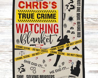 May include: A beige true crime watching blanket with the text "Chris's True Crime Watching Blanket" in red and black. The blanket features crime scene elements like footprints, question marks, and a detective silhouette. The blanket measures 127 x 152 cm.