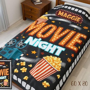Può includere: Coperta nera Movie Night con il nome "Maggie" e le parole "Movie Night" in arancione e bianco. La coperta presenta popcorn, bobine di film e una cinepresa vintage. Misura 152 x 203 cm.