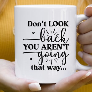 May include: White ceramic mug with black text that reads "Don't look back you aren't going that way..."