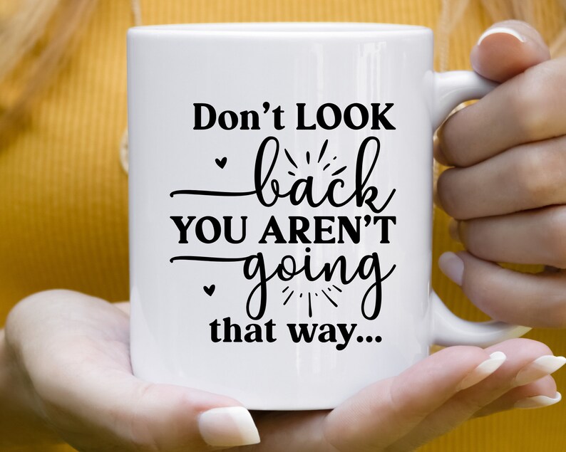 May include: White ceramic mug with black text that reads "Don't look back you aren't going that way..."