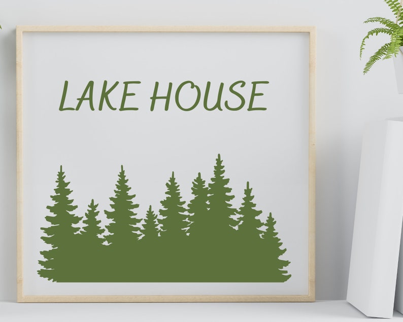May include: A framed print with the text "LAKE HOUSE" in green lettering. The print features a silhouette of a forest with green trees.