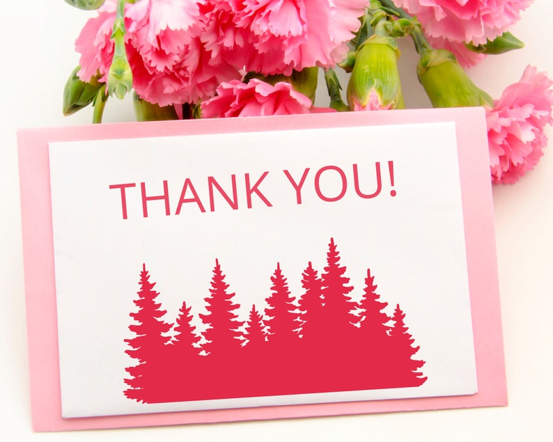 May include: A pink card with a white border and the text "THANK YOU!" in red. A red silhouette of a forest of pine trees is below the text.