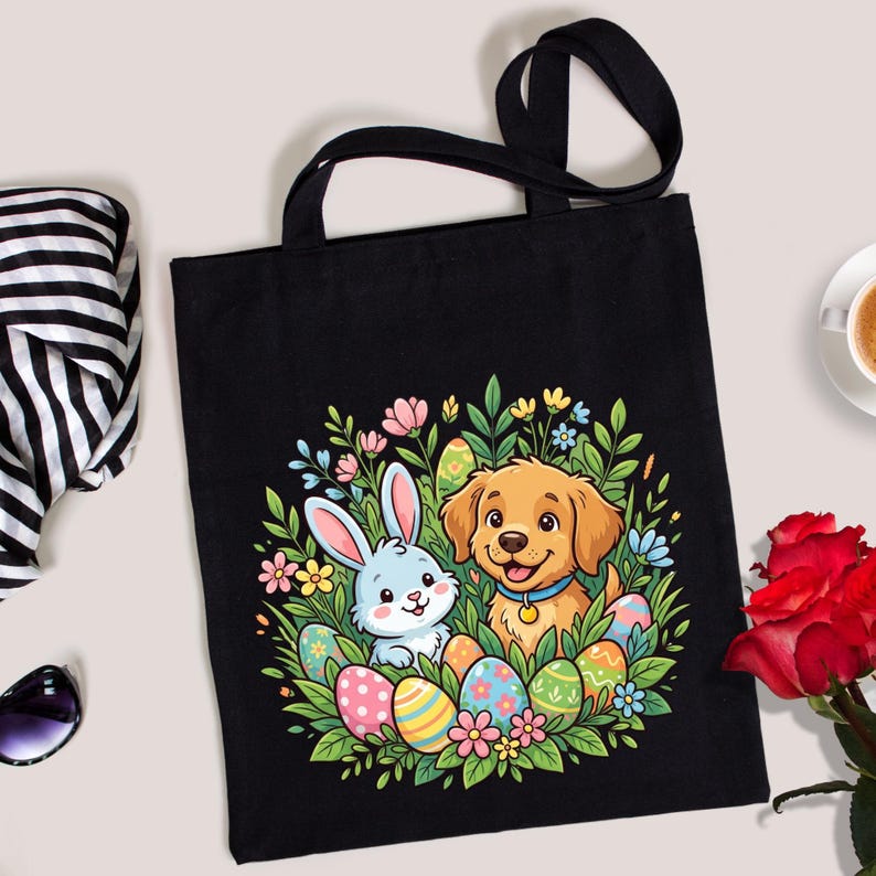 May include: A black tote bag featuring a colorful graphic of a light blue rabbit and a golden puppy surrounded by green foliage and patterned Easter eggs. The design is centered on the front of the bag, which has two black fabric shoulder straps.