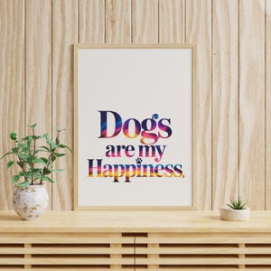 May include: Framed art print with the text "Dogs are my Happiness" in colorful, gradient lettering. The artwork is displayed on a wooden cabinet with a small potted plant and a succulent.