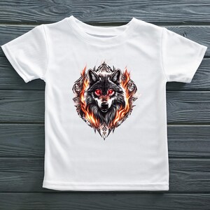 May include: White t-shirt with a graphic print of a wolf's head with red eyes surrounded by flames. The wolf is in a geometric design.