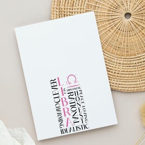 May include: White card with the word "LIBRA" in pink and black text, along with descriptive words like "charming" and "idealistic." A Libra symbol is above the word. The card is on a light background.