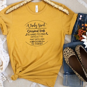 May include: A mustard yellow t-shirt with black text that reads "A Truly Great Surgical Tech is hard to find, difficult to part with and *impossible* to forget".