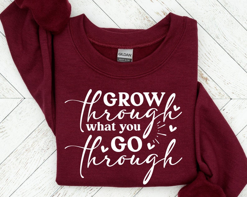 May include: Burgundy sweatshirt with white text that reads "GROW through what you GO through" with small hearts around the text.
