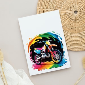 May include: A colorful illustration of a motocross bike with a rainbow splash effect. The bike features pink, yellow, orange, and blue accents. The background is black with a rainbow arc. The image is on a white card.