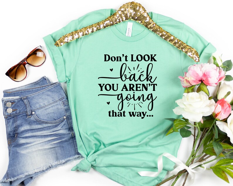 May include: Mint green t-shirt with black text that reads "Don't look back you aren't going that way..."
