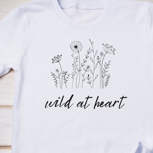 May include: White t-shirt with a black line drawing of wildflowers and the text "wild at heart".