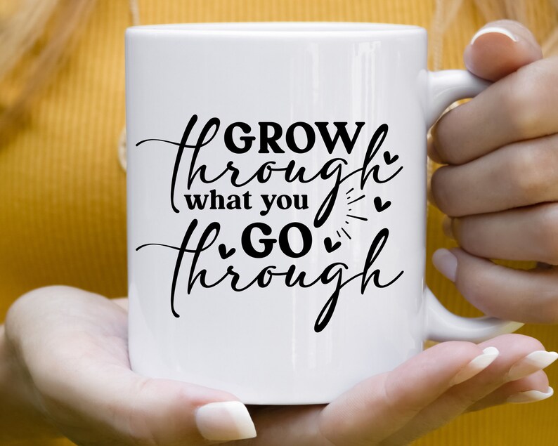 May include: White ceramic mug with black text that reads "GROW through what you GO through" with small hearts and a sunburst design.
