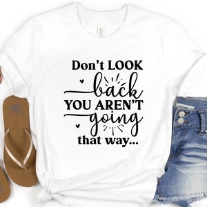 May include: White t-shirt with the text "Don't look back you aren't going that way..." printed in black.