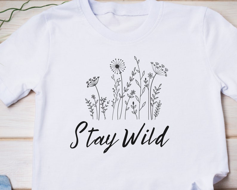 May include: White t-shirt with a black line drawing of wildflowers and the text "Stay Wild".