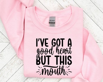 May include: Pink sweatshirt with black text that reads "I've got a good heart but this mouth".