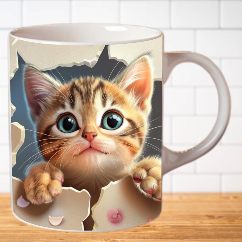 Pu&ograve; includere: Una tazza in ceramica bianca con un gattino tabby marrone e bianco che spunta da un buco strappato sul lato. Il gattino ha gli occhi azzurri e un'espressione carina.
