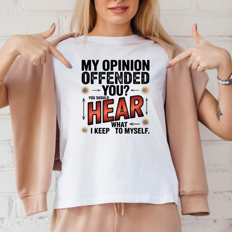 K&ouml;nnte beinhalten: Wei&szlig;es T-Shirt mit dem Text "MY OPINION OFFENDED YOU? YOU SHOULD HEAR WHAT I KEEP TO MYSELF." Der Text ist in Schwarz und Rot gehalten, mit dekorativen Elementen. Das T-Shirt wird gezeigt.