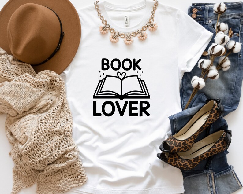 May include: White t-shirt with black text that reads "BOOK LOVER" and a graphic of an open book with a heart in the center.