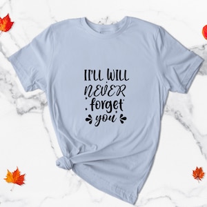 May include: Light blue t-shirt with the text "I'll will never forget you" in black lettering.