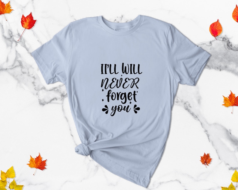 May include: Light blue t-shirt with the text "I'll will never forget you" in black lettering.