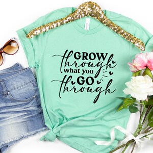 May include: A mint green t-shirt with the text "GROW through what you GO through" in black script with small hearts.