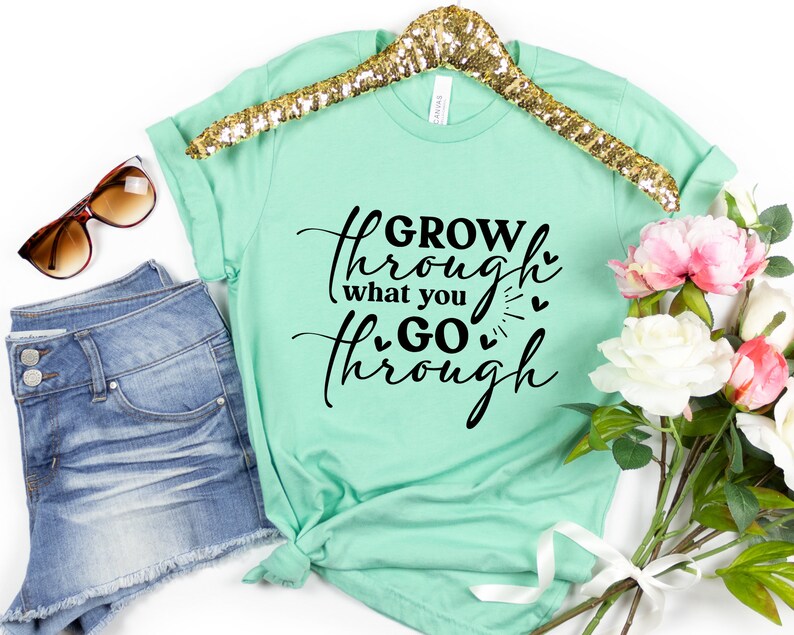 May include: A mint green t-shirt with the text "GROW through what you GO through" in black script with small hearts.