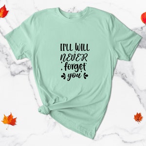 May include: A light green t-shirt with the text "I'll will never forget you" in black.
