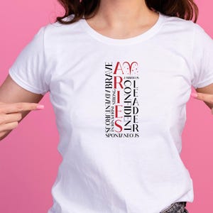 May include: White t-shirt with the word "ARIES" in red and black vertical text. Additional words describe Aries traits: ambitious, brave, confident, independent, adventurous, strong, leader, and spontaneous.