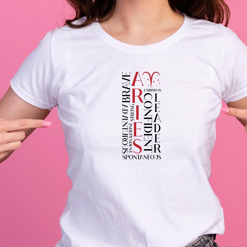May include: White t-shirt with the word "ARIES" in red and black vertical text. Additional words describe Aries traits: ambitious, brave, confident, independent, adventurous, strong, leader, and spontaneous.