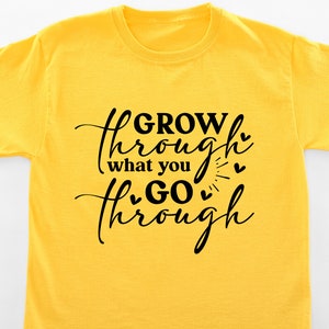 May include: Yellow t-shirt with black text that reads "GROW through what you GO through" with small hearts around the text.