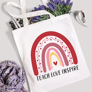 May include: White canvas tote bag with red, pink, and yellow rainbow design and the text "Teach Love Inspire".