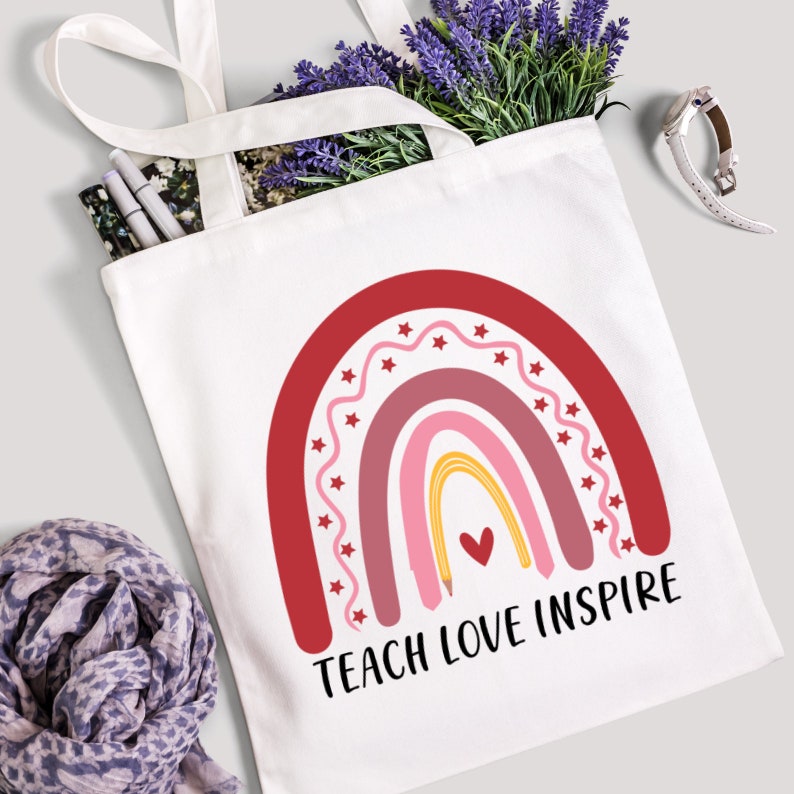 May include: White canvas tote bag with red, pink, and yellow rainbow design and the text "Teach Love Inspire".