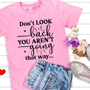 May include: Pink t-shirt with black text that reads "Don't look back you aren't going that way..."