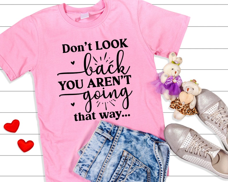 May include: Pink t-shirt with black text that reads "Don't look back you aren't going that way..."