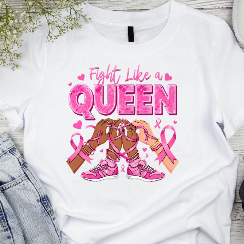 May include: White t-shirt with a pink graphic that reads "Fight Like a QUEEN." The design includes pink ribbons, hearts, and illustrations of hands and pink sneakers. The shirt is a crew neck style.