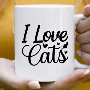 Może przedstawiać: Biały kubek ceramiczny z czarnym nadrukiem "I Love Cats" z sylwetką kota i sercami.