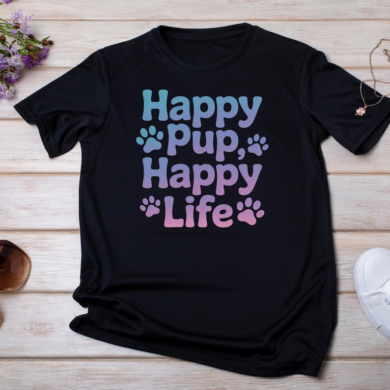 May include: Black t-shirt with the words "Happy Pup, Happy Life" in a gradient of blue and pink. The design includes paw prints. The shirt is made of a soft material.