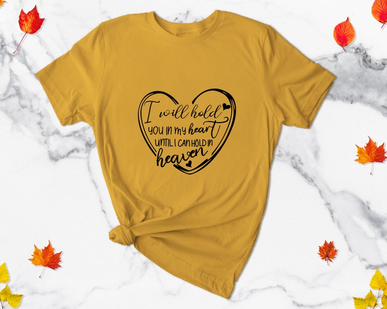 May include: A mustard yellow t-shirt with a black heart graphic and the text "I will hold you in my heart until I can hold in heaven".