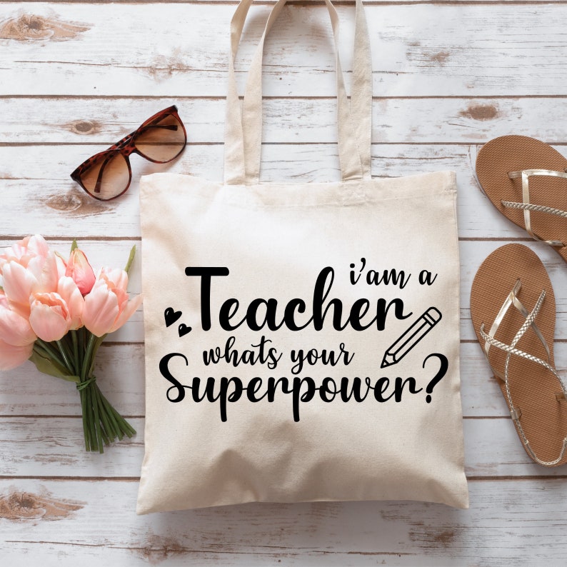 May include: A white canvas tote bag with black text that reads "I'm a Teacher, what's your superpower?" with a pencil icon.