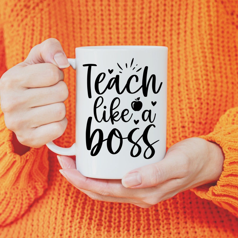 May include: White ceramic mug with a black graphic that says "Teach like a boss" with a small apple and hearts.