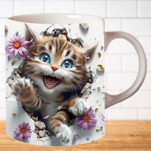 Pu&ograve; includere: Tazza in ceramica bianca con un'immagine colorata di un gattino che spunta da un muro screpolato. Il gattino ha gli occhi azzurri e sorride a bocca aperta. Ci sono fiori rosa intorno al gattino.