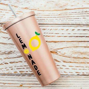 Puede incluir: Un vaso de color rosa dorado con un gr&aacute;fico de lim&oacute;n negro y amarillo y el texto "LEMONADE".